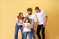 Friendly family, redhead young men, woman and kid wearing casual style clothes using tablet, doing online shopping. Royalty Free Stock Photo