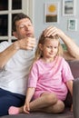 A friendly family from young father and little daughter sit near on the sofa in the room. A caring dad decorates his Royalty Free Stock Photo