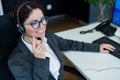 A friendly female call center operator at the desk. The woman in the headset answers the customer`s call. Royalty Free Stock Photo