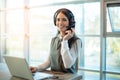 Friendly female customer support representative in headset with microphone consulting client at call center office. Royalty Free Stock Photo