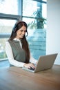 Friendly female customer support representative in headset with microphone consulting client, using laptop in the office Royalty Free Stock Photo