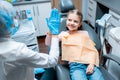 Friendly female dentist giving high five little girl sitting on stomatological chair after treatment