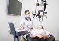 Friendly female dentist with patient during dental procedure with microscope in dental office Royalty Free Stock Photo