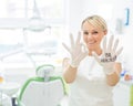 Friendly female dentist smiling and showing okay sign with fingers. Blonde doctor in gloves in the office in the medical Royalty Free Stock Photo