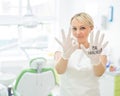 Friendly female dentist smiling and showing okay sign with fingers. Blonde doctor in gloves in the office in the medical Royalty Free Stock Photo