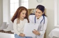 Friendly doctor communicating with little girl and showing her clipboard with prescription