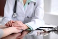 Friendly female doctor hands holding patient hand sitting at the desk for encouragement, empathy, cheering and support