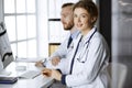 Friendly female doctor sitting in clinic with her male colleague at the background. Perfect medical service and medicine Royalty Free Stock Photo