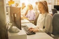 Friendly female helpline operator with headphones working on computer in call center Royalty Free Stock Photo