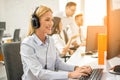 Friendly female helpline operator with headphones working on computer in office. Royalty Free Stock Photo