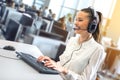 Friendly female helpline operator working on her workspace at large busy call center office. Royalty Free Stock Photo