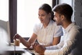 Friendly female mentor training male employee with computer