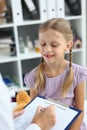 Friendly female pediatrician doctor holding clipboard listening to child girl Royalty Free Stock Photo