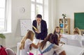 Friendly female teacher walks around classroom during lesson and gives hints to students. Royalty Free Stock Photo