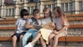Friendly group of kids reading book outdoors.