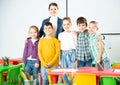 Friendly group of pupils with female teacher in schoolroom