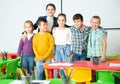 Friendly group of pupils with female teacher in schoolroom