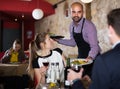 Friendly guy waiter serving meals to young couple Royalty Free Stock Photo