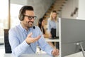 Friendly handsome male call centre executive worker talking to client in support service office Royalty Free Stock Photo