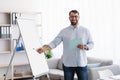 Friendly happy adult european male teacher with beard in glasses shows on blackboard teaches students Royalty Free Stock Photo