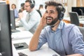 Friendly happy handsome young man with hands-free headset using computer in a call centre. Royalty Free Stock Photo