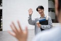 A friendly Asian male college student is waving his hand to say hi to his friends Royalty Free Stock Photo