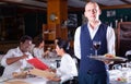 Friendly headwaiter with serving tray welcoming in restaurant Royalty Free Stock Photo