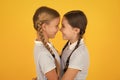 Friendly hug. Cute schoolgirls. Girls braided hairstyle. Cheerful schoolgirls yellow background. Little girls playing