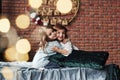 Friendly hugs. Little girls having fun on the bed with holiday interior at the background