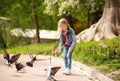 Friendly joyful girl child feeds pigeons in city summer park