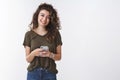 Friendly joyful young woman testing new smartphone app smiling cheerfully look camera delighted distracted from righting