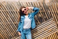 Friendly laughing girl in jeans suit making a peace sign. Smiling female model in striped sweatshirt posing next to