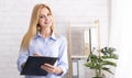 Friendly life coach standing with clipboard in office