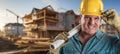 Friendly Male Contractor at a Construction Site Wearing a Hard Hat and Work Gloves Holding His Blueprint Plans Royalty Free Stock Photo