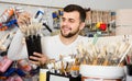 friendly male customer examining various types of brushes in paint store Royalty Free Stock Photo