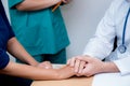Friendly male doctor hand holding patient hand sitting at the desk for encouragement Royalty Free Stock Photo