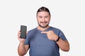 A friendly man in his 30s showing his smartphone. Pointing to the cellphone with his index finger. Advertising an app Royalty Free Stock Photo