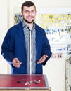 Friendly man worker displaying result of his key making in workshop Royalty Free Stock Photo