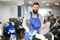 Friendly man worker displaying various motorcycles in workshop Royalty Free Stock Photo