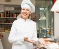 Friendly mature female seller offering sweets Royalty Free Stock Photo