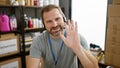 Friendly mature man with headset waving in a busy warehouse environment Royalty Free Stock Photo