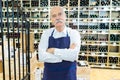 Friendly mature seller standing in wine house Royalty Free Stock Photo