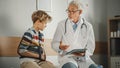 Friendly Middle Aged Family Doctor Talking with a Young Boy with Arm Brace and Showing Test Results Royalty Free Stock Photo