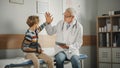 Friendly Middle Aged Family Doctor Talking with a Young Boy with Arm Brace and Showing Test Results Royalty Free Stock Photo