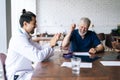 Friendly multi-ethnic team of doctors congratulate happy mature male physician leader winner applaud Royalty Free Stock Photo