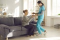 Friendly nurse at hospital or assisted living facility giving glass of water to mature woman