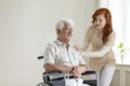 Friendly nurse supporting smiling paralyzed senior man in a whee Royalty Free Stock Photo