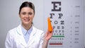 Friendly oculist recommending carrot for maintaining good vision, healthy food Royalty Free Stock Photo