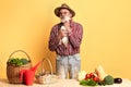 Friendly old farmer stands near vegetables and basket with eggs, hugs hen Royalty Free Stock Photo