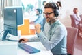 Friendly operator with hands-free headset talking with client during online phone call giving adequate answers to client Royalty Free Stock Photo